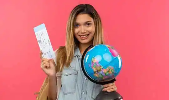 Girl flashing Air ticket while carrying mini globe on the other hand 