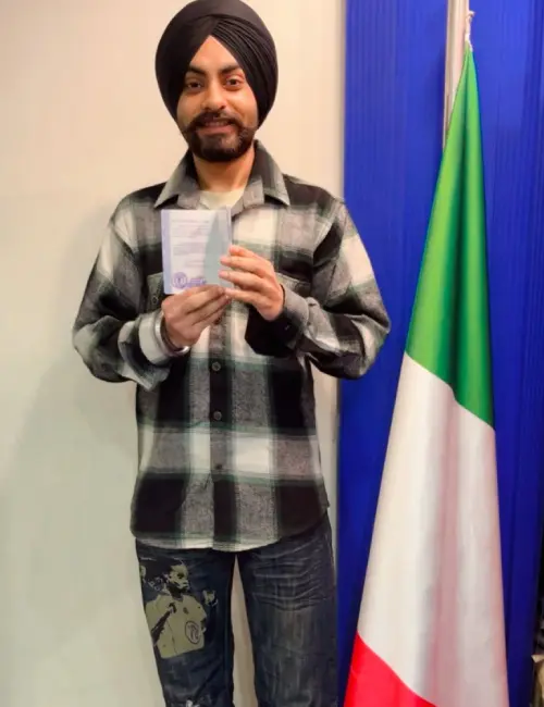 Gagandeep Singh is standing with the Italian flag while holding his passport in hand