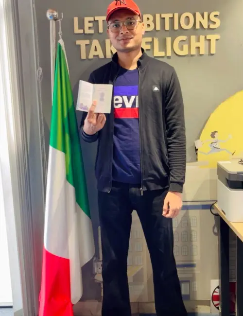 Gagandeep Singh is standing with the Italian flag while holding his passport in hand